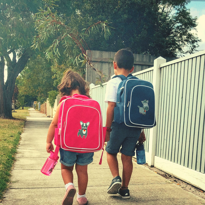 Kids walking away, wearing Jordbarn kids backpacks and holding matching kids water bottles